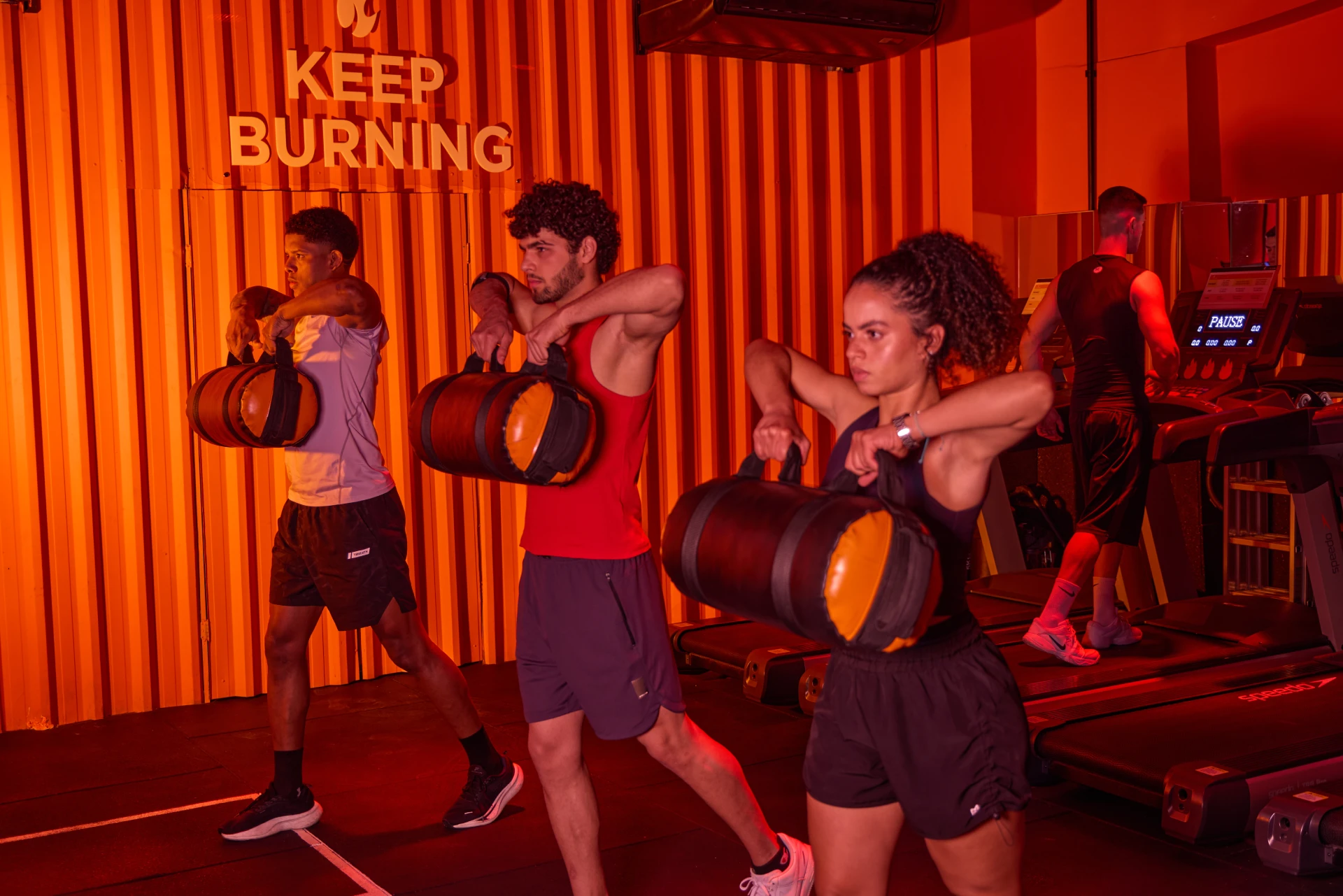 Grupo de alunos em movimento sincronizado com sandbag, parede Keep Burning ao fundo